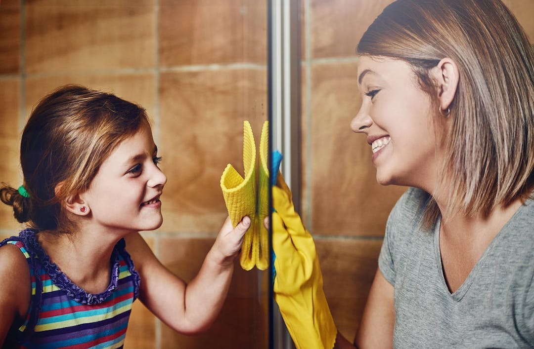 A woman and a child cleaning a glass door